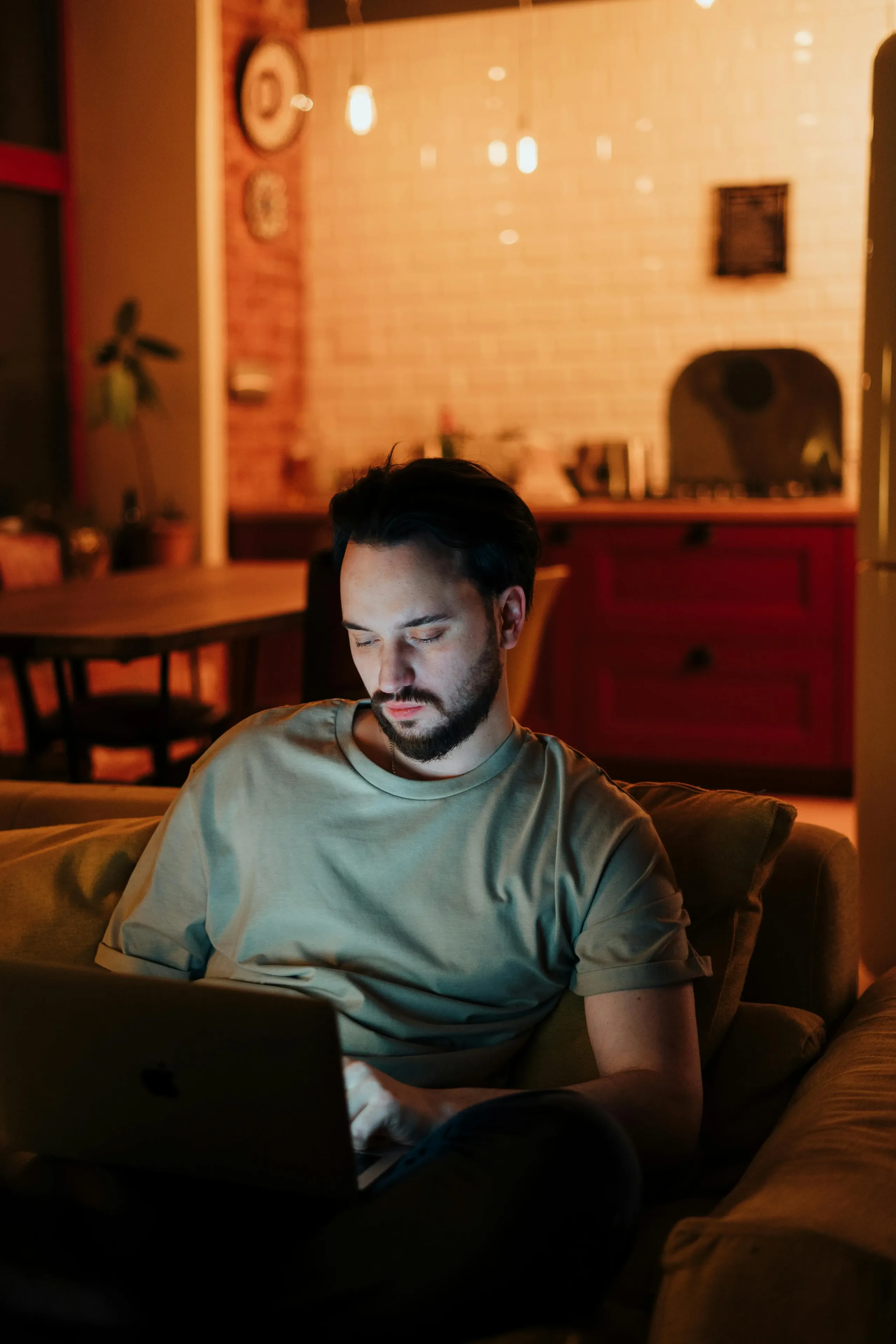 A person working on a laptop in a dimly lit living room in the evening.